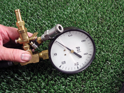 Photo 4: A water pump pressure test adapter can be created by tapping the inner bore of a 5/8” hose connecter to 1/8” pipe thread. The adapter is then attached to a pressure gauge using 3/8” hose barbs and rubber hose.