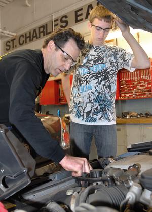 St. Charles East High School teacher Tom Straiker, left, and junior Johnny Apida check over the engine on a vehicle during Advanced Auto Tech class at the school Tuesday Apr. 27. (Photo by Mark Busch)