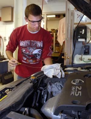 St. Charles East High School senior and service manager James Kerley checks the oil on a vehicle during Advanced Auto Tech class at the school Tuesday Apr. 27. (Photo by Mark Busch)